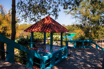 Summer gazebo with red roof tiles among the tropical greenery.