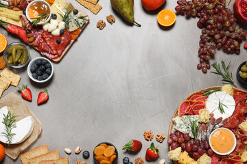 Frame of different delicious snacks on grey table, flat lay. Space for text