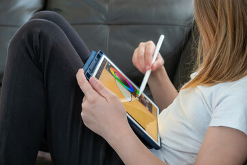 Girl digital artist draws with a stylus on a tablet or laptop. She is a student and is studying...