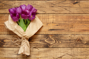 Purple tulips bouquet on wooden table