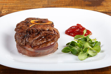 Meat with herbs and ketchup on a white plate. Board.
