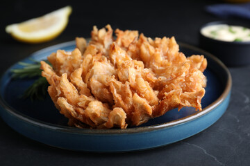 Delicious onion blossom served on black table, closeup