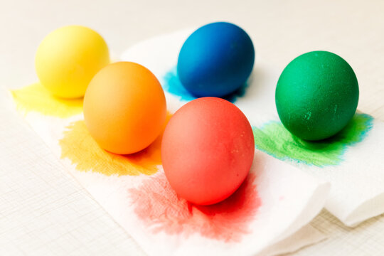 Close-up of stage of drying painted eggs after painting process in food coloring. Home decorations for the holiday. The main symbol of Easter. Bright color: yellow, orange, red, green and blue. Five