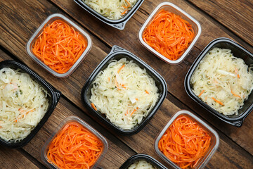 Plastic containers with tasty vegetable salads on wooden table, flat lay. Food delivery service