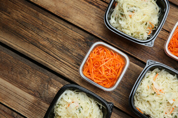Plastic containers with tasty vegetable salads on wooden table, flat lay and space for text. Food delivery service