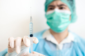 Asian doctor holding medical syringe,preparing a vaccine or a serum for injection to a patient,treatment with a vaccine to produce immunity fight against the COVID-19,inoculation,vaccination concept