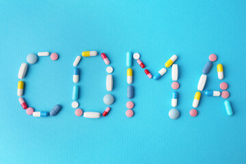 Word Coma made of pills on light blue background, flat lay
