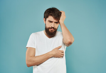 A brunette guy with a thick beard on a blue background gestures with his hands cropped view