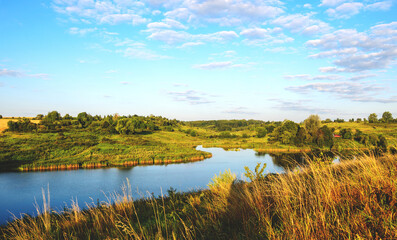 Fototapeta na wymiar Summer serene landscape with calm river and green hills at sunrise.