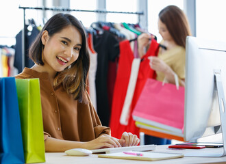 Asian saleswoman using computer in clothes store