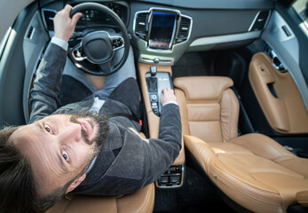 Funny wide angle of a male driver in luxury car