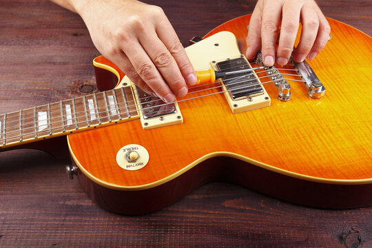 Guitar master adjusts intonation on electric guitar at workplace.