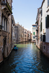Fototapeta na wymiar Beautiful narrow canal with gondolas and small boats and historical buildings in Venice, Italy