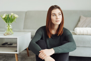 Wistful young woman staring out of a window with a pensive expression