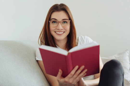 Friendly young woman relaxing at home with a large book