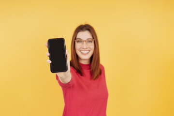 Smiling happy woman holding out her mobile phone