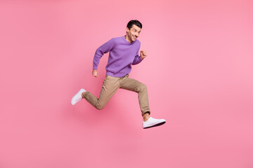 Fototapeta na wymiar Photo of funny purposeful young man dressed purple pullover jumping hurrying isolated pink color background
