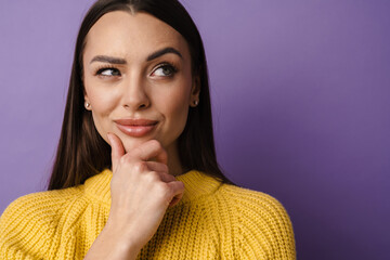 Pensive young woman in sweater touching her face with hands