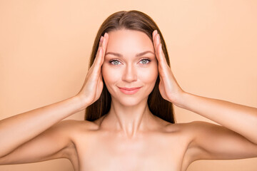 Fototapeta premium Portrait of attractive dreamy girl touching demonstrating perfect facial form oval isolated over beige pastel color background