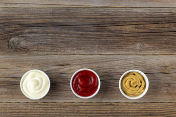 Set of three kinds of classic sauces on wooden background. Mayonnaise ketchup mustard