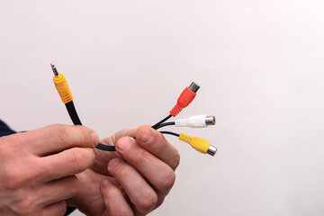 Cable. Audio video cable RCA jack in a man's hands on a white background. RCA plugs for video and stereo audio.