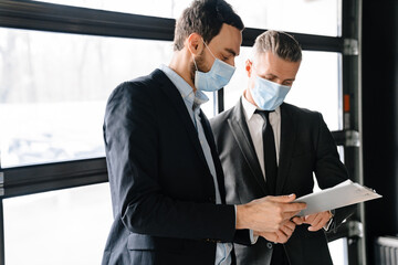 Focused brunette manager in face mask discussing contract with customer
