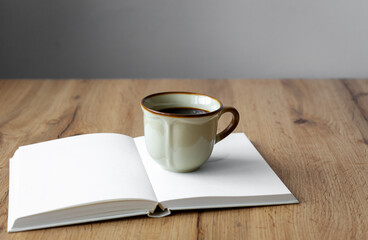 Eine rustikale Kaffeetasse auf einem offenen Buch auf einem braunen Holz Tisch. Vintage Stil, Zuhause.