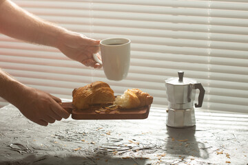 Breakfast with croissant on cutting board and black coffee. Morning meal and breakfast concept.