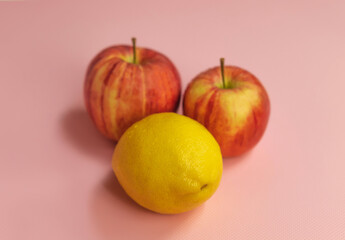 Fresh and ripe apples with lemon in the center on a pink background