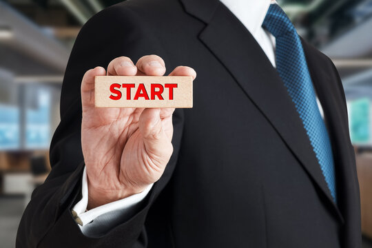 Businessman shows a wooden block with the word start
