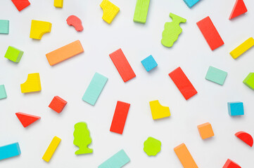 Multi-colored children's constructor made of natural wood on light gray background flat lay top view. Colored children's bricks for construction. Building blocks background. Developing toys, game