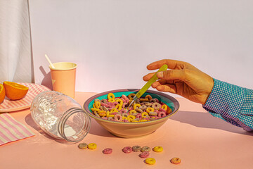 Arm of woman eating colors cereals with milk at vintage kitchen