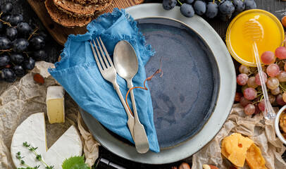 Empty serving blue plate with fork spoon in frame of food grocery ingredients Mediterranean Kitchen. Blue plate dish in frame of food wine cheese bread grapes. Flat lay Long web banner