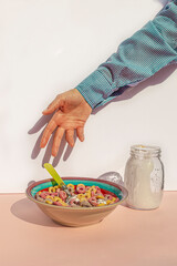 Arm of woman eating colors cereals with milk at vintage kitchen