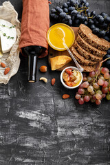 Food snacks Ingredients different cheeses grapes honey wine bread on dark concrete background. Wine and cheese composition. Mediterranean Kitchen Food drink gastronomy. Copy space on chalkboard 