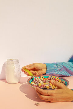 Arm of woman eating colors cereals with milk at vintage kitchen