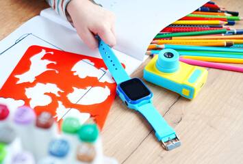 Children's hand holding a smart watches with wiretapping, remote monitoring and GPS tracker.