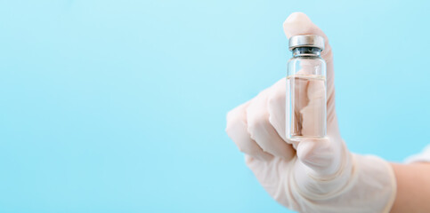 Covid 19 coronavirus Vaccine in glass vial bottle, medicine liquid in doctor hand. Mock up Vaccination injections as treatment. Covid immunization concept Long banner on color background copy space