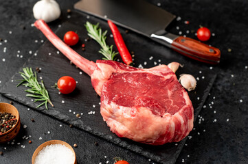 raw tomahawk beef steak on the knife with spices on stone background