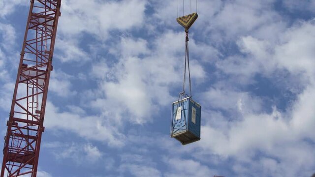 The mobile toilet is lifted by the crane on the construction site.