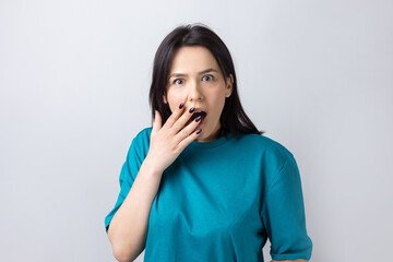 Young beautiful woman with facial expression of surprise standing over gray background.