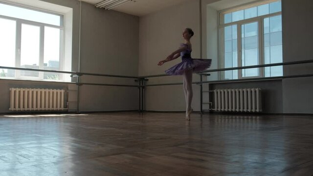 A teenage ballerina in a beautiful tutu trains and dances beautifully. Filmed in a dance studio.
