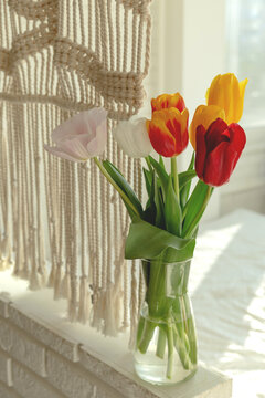 Beautiful spring multicolored tulips in a light interior next to macrame. High quality photo