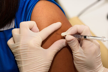 Close-up view of needle injecting vaccine on a woman arm