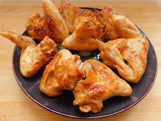Baked chicken wings in pan on wooden table.
