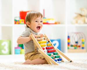 Little child boy playing with toy blocks. Baby in nursery or kindergarten - obrazy, fototapety, plakaty