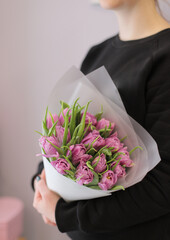Young woman florist holding big beautiful blossoming mono bouquet of purple peonies tulips flowers.