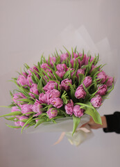 Young woman florist holding big beautiful blossoming mono bouquet of purple peonies tulips flowers.