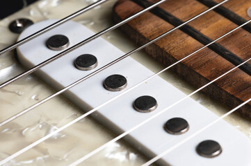 Guitar fretboard with tuning pegs and strings on a gray background. Close-up