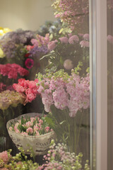 Showcase with vases with different colored roses, tulips, peonies in flower shop. Beautiful spring bouquets. Small family business. Work florist.